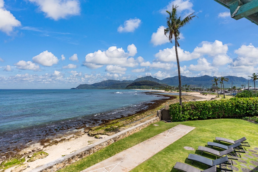 Oceanfront paradise with manicured lawn leading directly to pristine beach and dramatic mountain coastline.