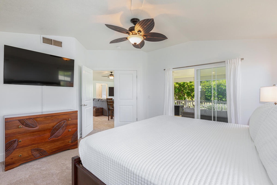 Airy primary bedroom with ceiling fan and direct garden views.