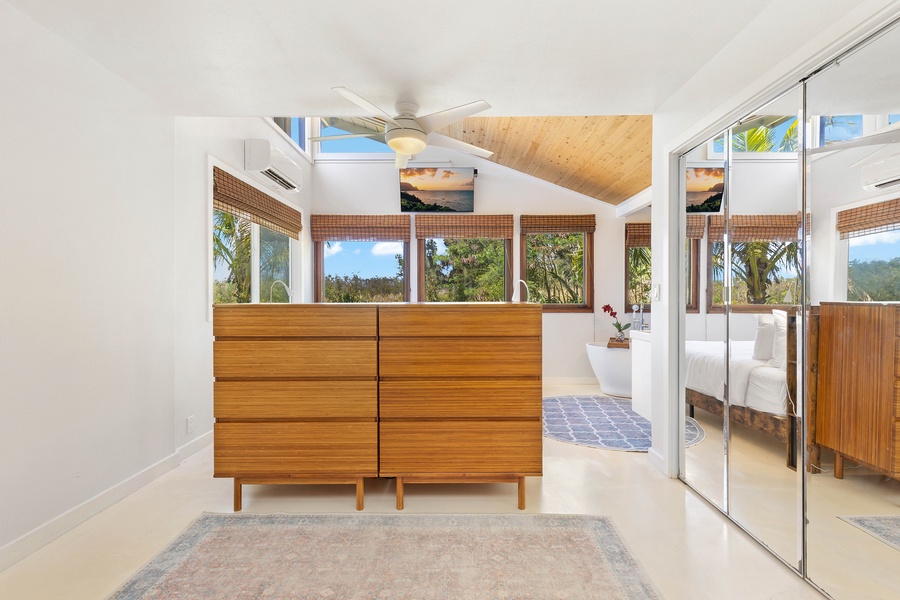 The primary bedroom offers warm wood ceilings, abundant light, and direct lanai access.