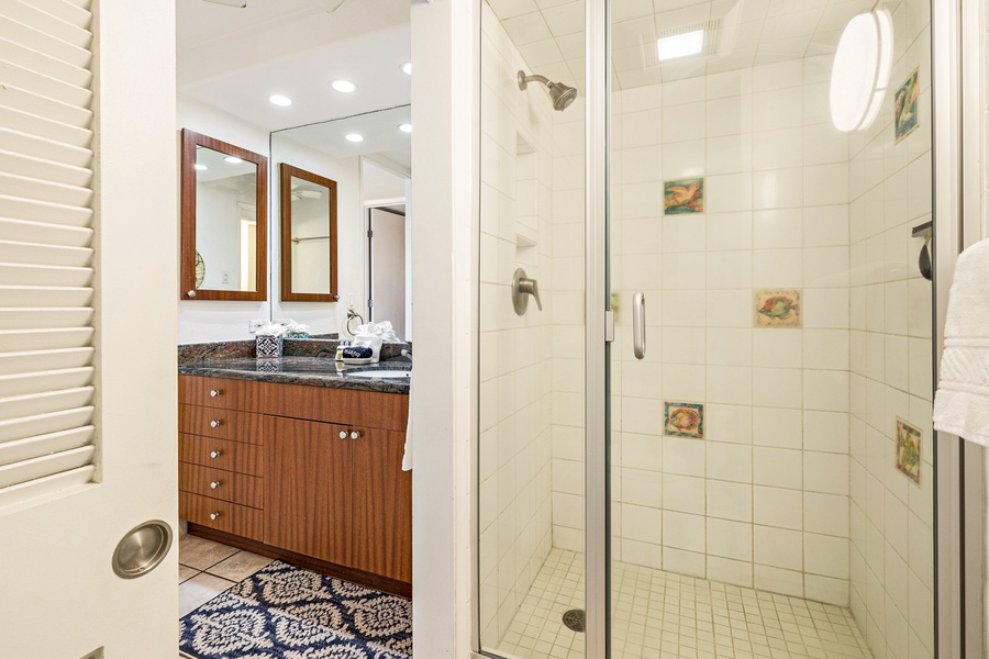 This bathroom showcases a spacious walk-in shower with a glass door and charming tile details