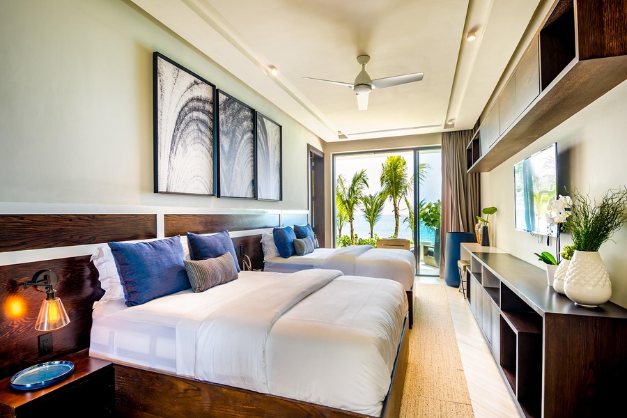 Spacious guest bedroom with modern decor and ocean views through floor-to-ceiling windows.