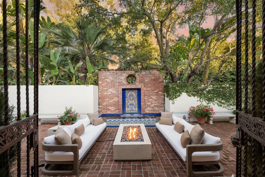 Your private courtyard awaits with plush seating around a crackling fire pit, surrounded by lush palms and tropical greenery.