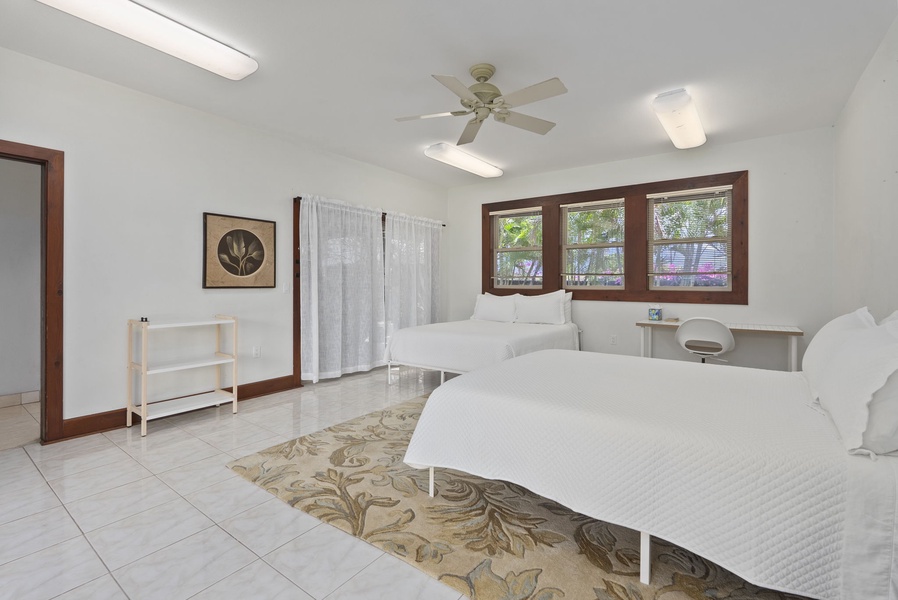 Guest bedroom with two beds, ceiling fan, and abundant natural light.
