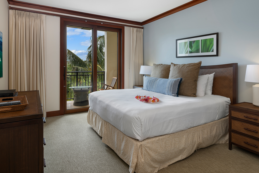 The primary bedroom with a private lanai with golf course views, features king size bed, luxury linens, and storage.