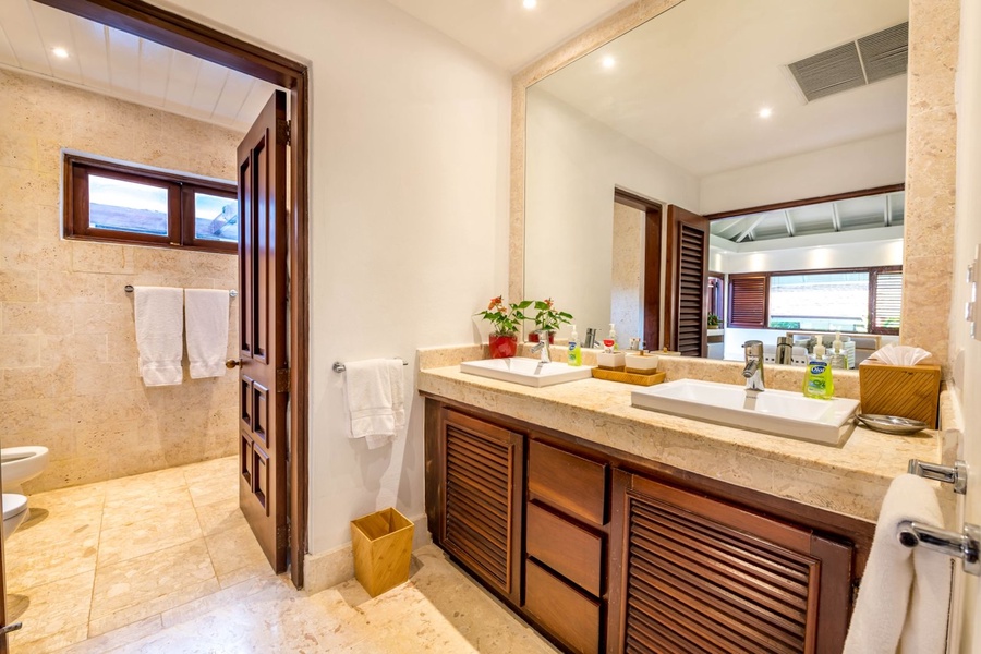 Full ensuite bathroom with wooden accents and ample lighting.
