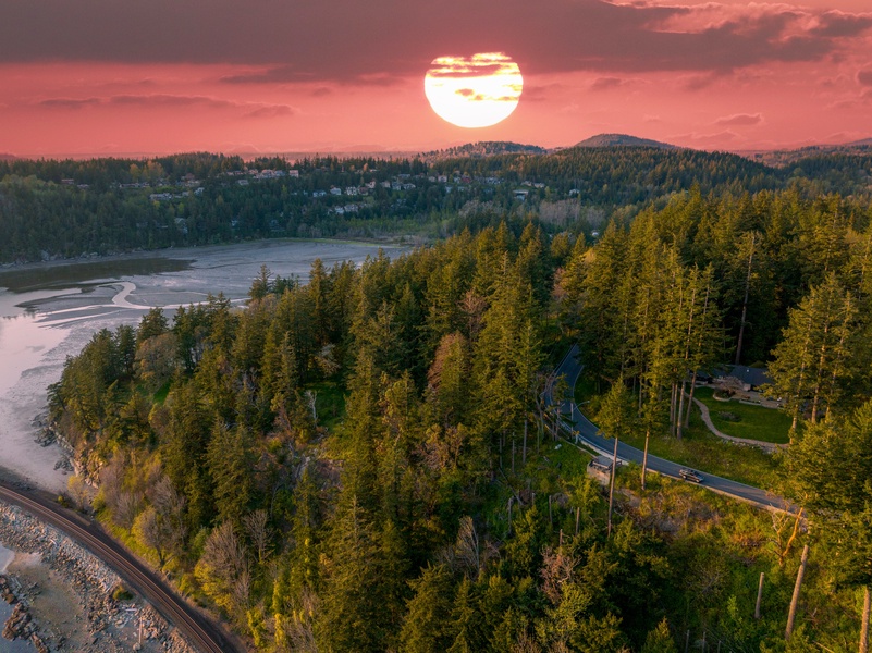 Sunset aerial view of the forested coastline, highlighting the natural beauty of the surrounding area.