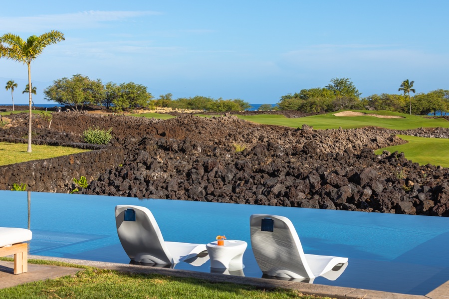 Stunning infinity pool overlooks volcanic landscape and championship golf course on Hawaii's pristine coastline.