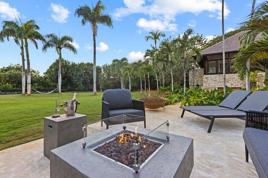 Gather in the fire pit featuring plush seating and tropical views.