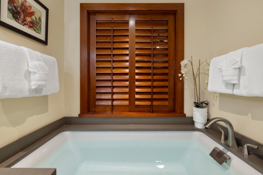 Sink into your private soaking tub surrounded by warm wood shutters and crisp white linens—your perfect retreat awaits.