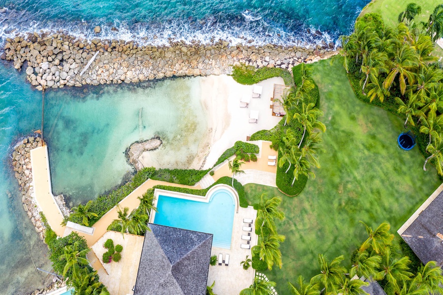Aerial view of the crystal-clear waters, lush greenery, and luxurious amenities at Villa Miramar.