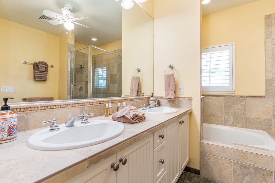 The primary guest bathroom with a double vanity, bathtub and shower.