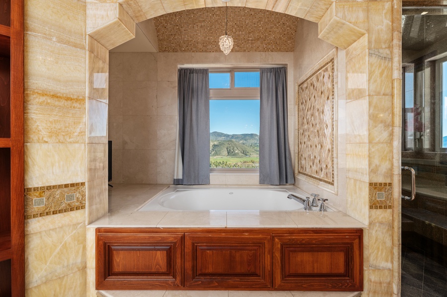 A soaking tub set into an arched alcove, the window framing the hills.