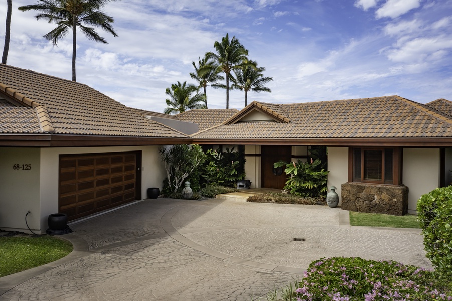 Elegant tropical property with circular driveway, lush landscaping, and swaying palm trees creating a peaceful island retreat atmosphere.