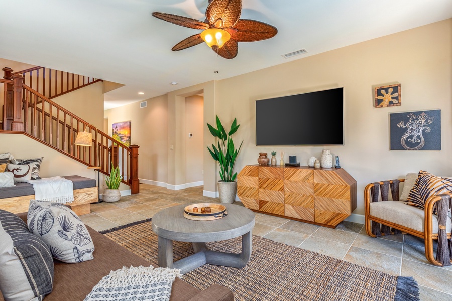 Artfully appointed downstairs living area with couch, pune'e (Hawaiian daybed), and smart flatscreen TV.