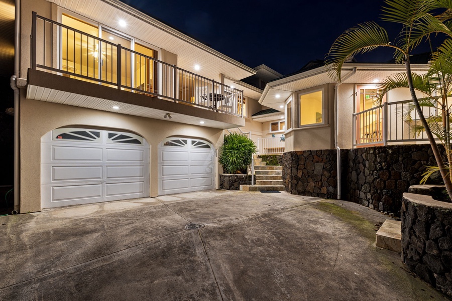 Beautiful two-story property with elegant stone accents and tropical landscaping, featuring a spacious driveway and convenient garage access.