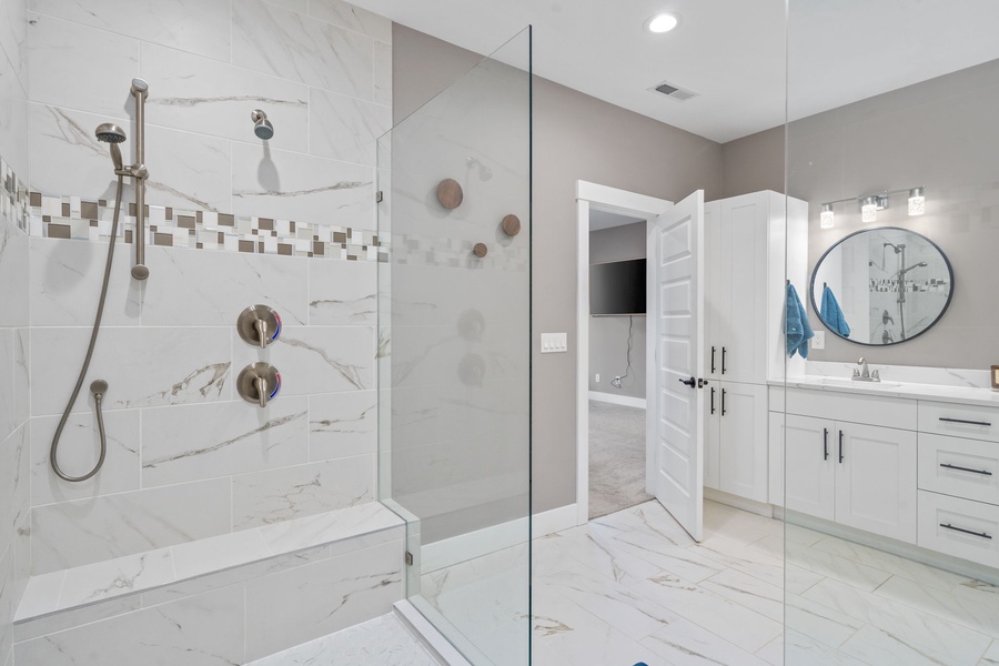 Spa-like bathroom with elegant marble finishes and a spacious glass-enclosed shower featuring dual heads.