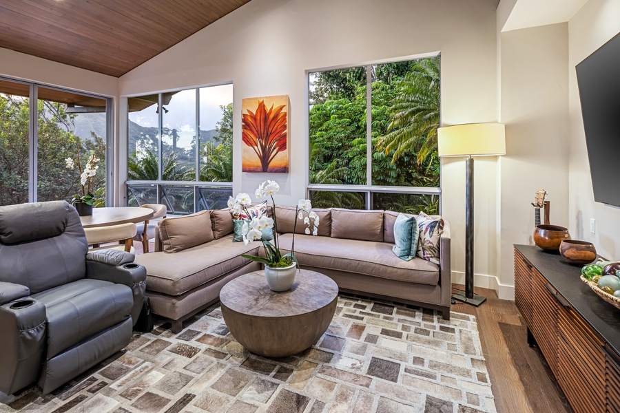 Relax in the cozy media lounge with plush recliners and smart TV, framed by tropical scenery.