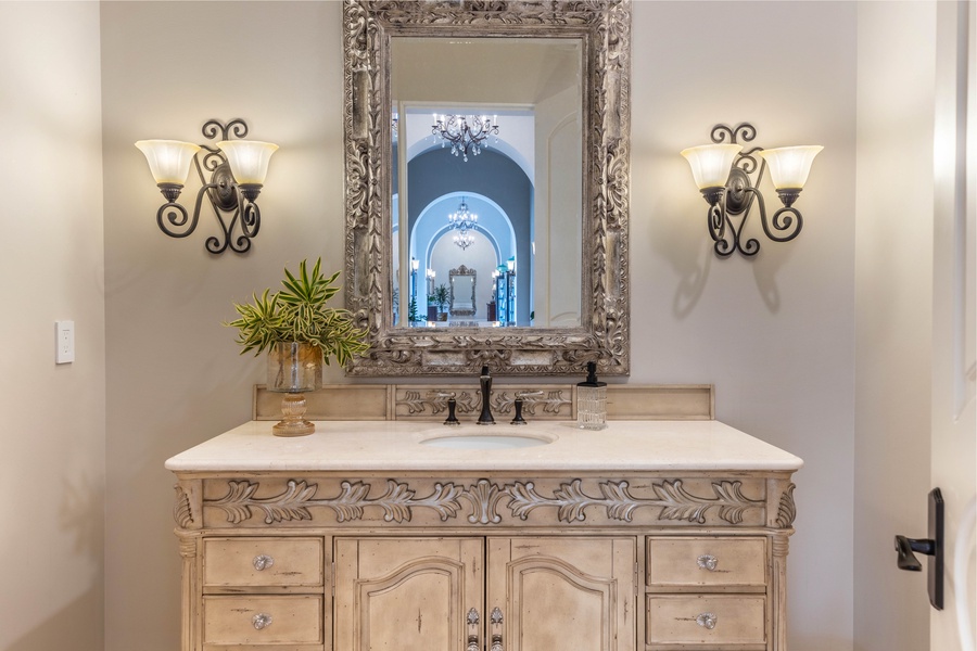 Ornate vanity with intricate detailing, complemented by warm lighting and a decorative mirror.