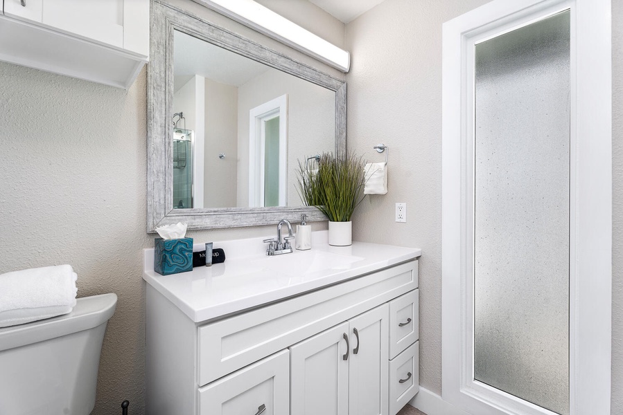 Upstairs bathroom with single vanity and wide mirror, located near guest bedrooms.