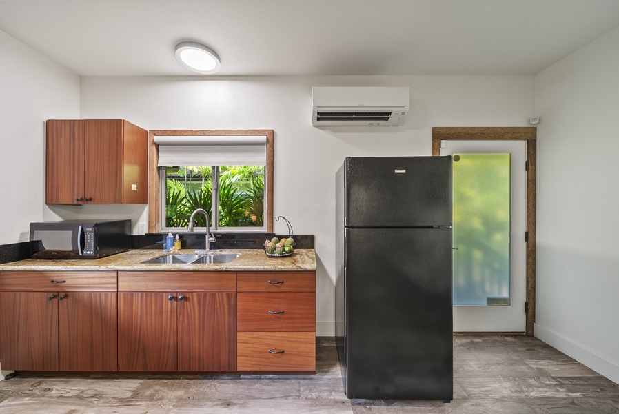 Detached guest suite kitchenette with mini fridge, wood cabinetry, and A/C—ideal for added independence.