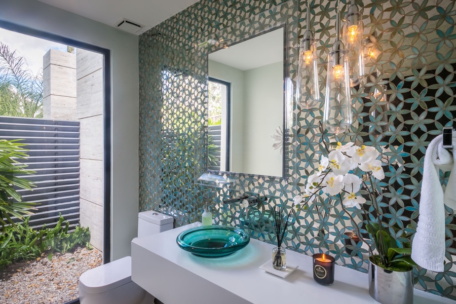 Pamper yourself in this stylish bathroom with unique tile work and a modern sink.