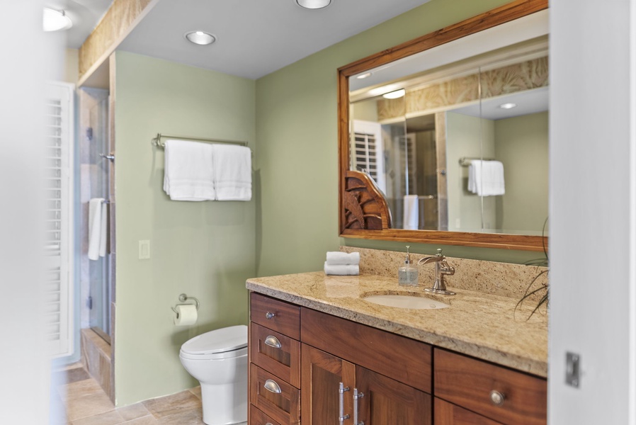 Granite countertop and wood cabinetry give this bathroom a warm, upscale feel with all the essentials for a comfortable stay.