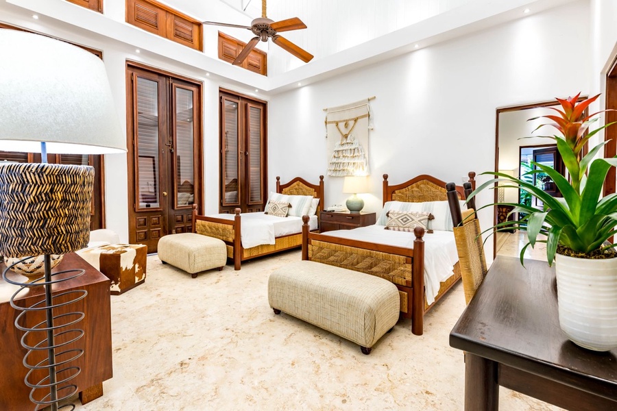 Bright guest bedroom with two comfortable beds and matching ottomans.