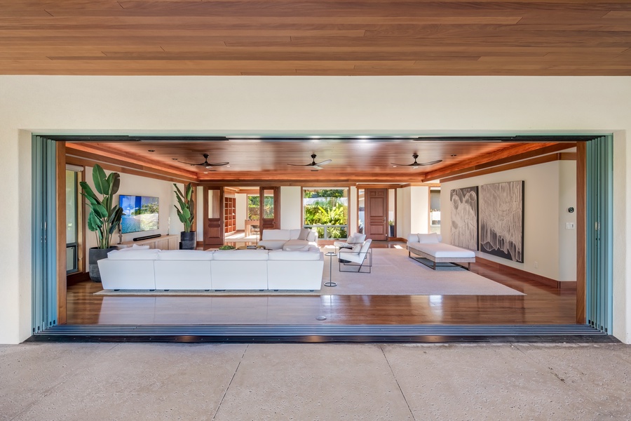 Bright and airy living room with expansive pocket doors connecting to outdoor spaces. Looking from back lanai towards front door.