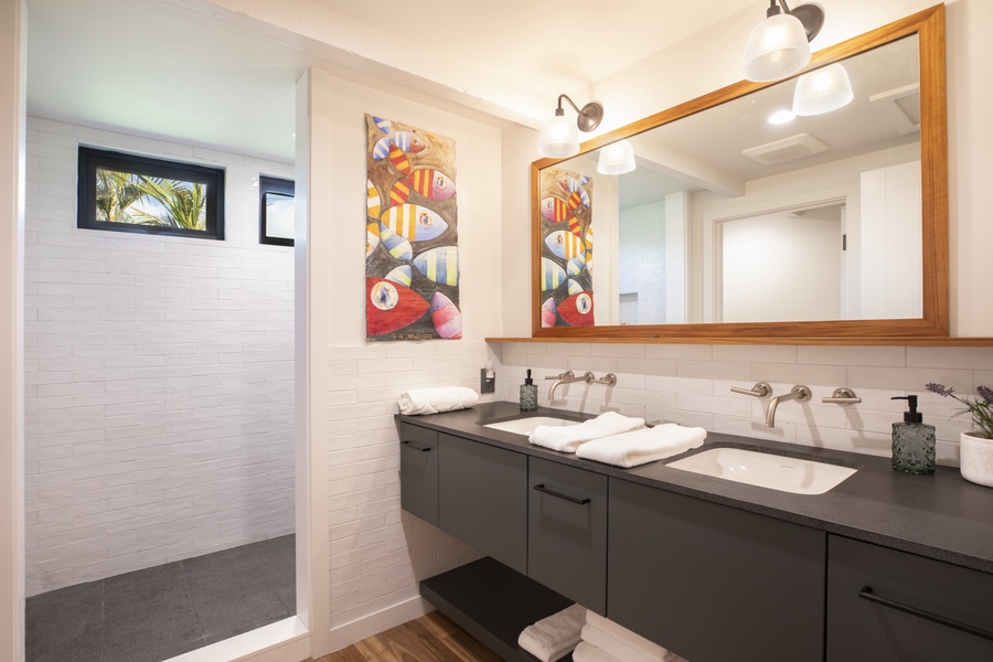 Elegant bathroom with dual sinks, vibrant artwork, and well-lit mirrors.