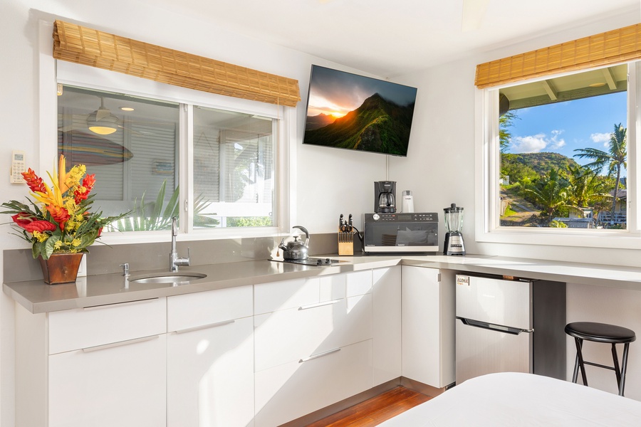 The studio kitchenette is stocked with essentials, featuring a sink, microwave, coffee maker, and mini fridge.