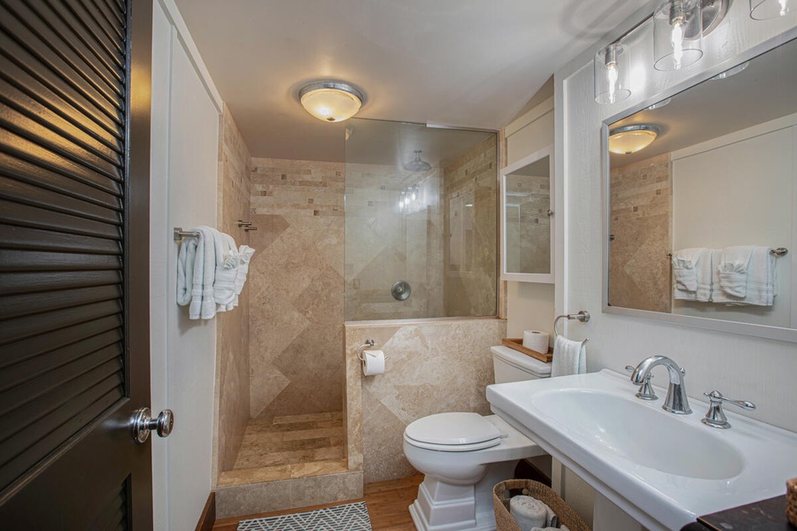 Elegant en-suite bath with walk-in shower, modern tilework, and natural stone finishes.