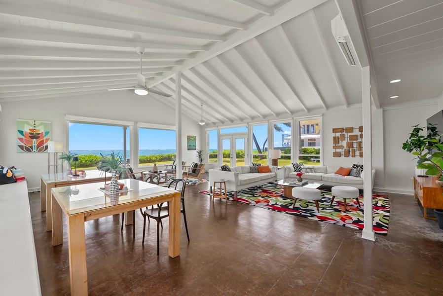 Relax in this bright, open living space with soaring vaulted ceilings, colorful accents, and floor-to-ceiling windows framing stunning ocean views—your perfect coastal retreat.