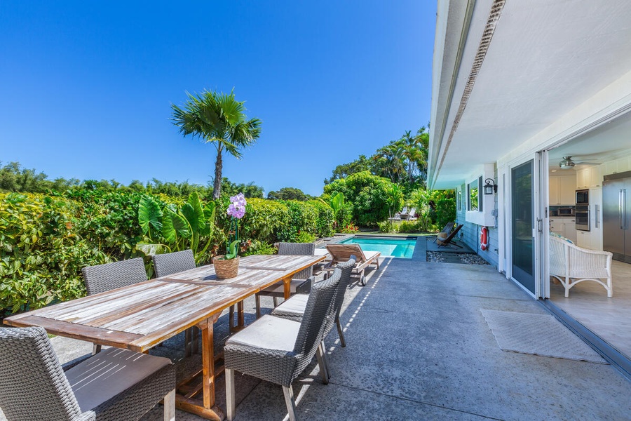 Alfresco dining area by the pool equipped with a spacious table and comfortable seating.