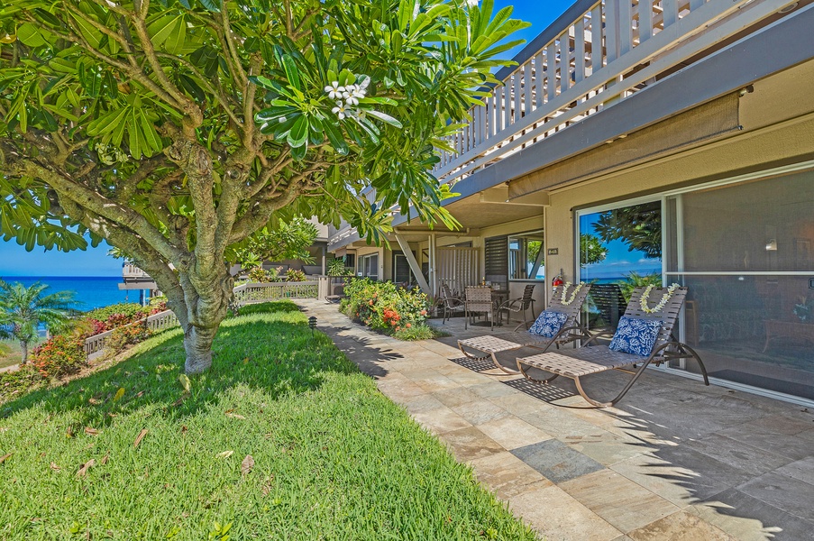 Relax on the lanai, surrounded by lush greenery, with comfortable seating perfect for enjoying the ocean breeze and island scenery.