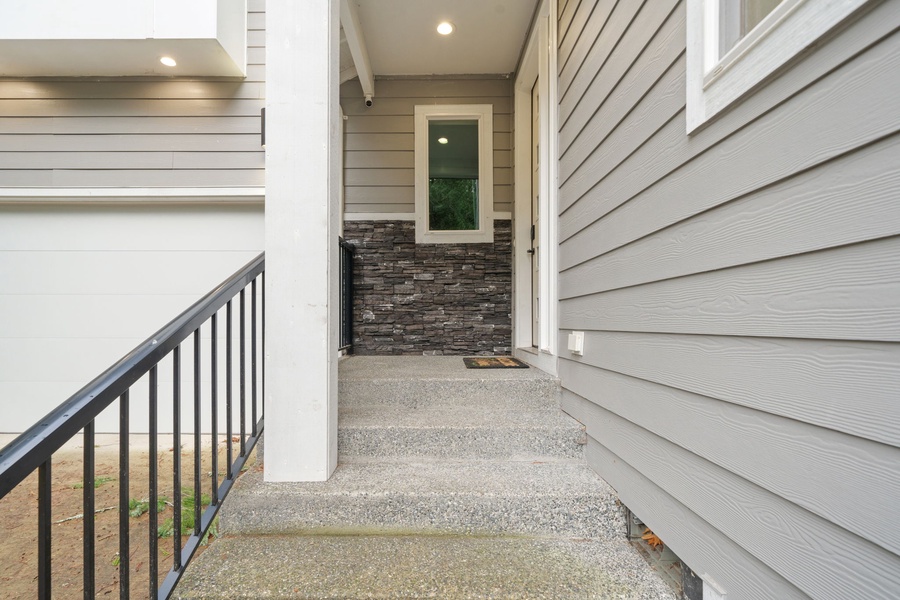Modern entrance with stone accent wall and covered entryway provides an elegant arrival experience.