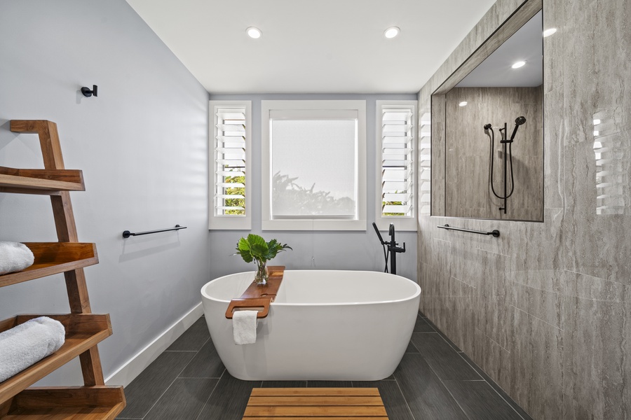 Primary bath with soaking tub, custom shower and views of the greenery outdoors.