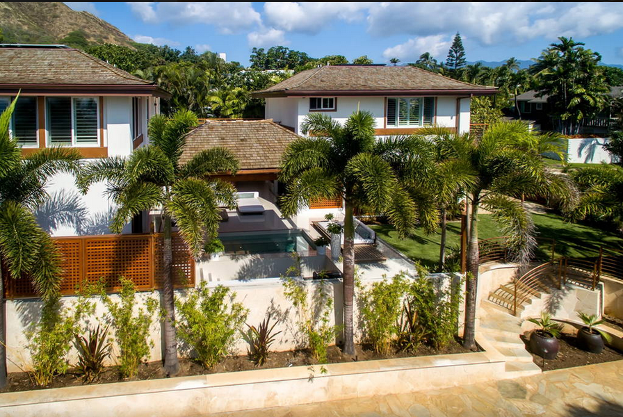 Lush landscaping frames the villa’s private entry and courtyard—welcoming, tropical, and secure.