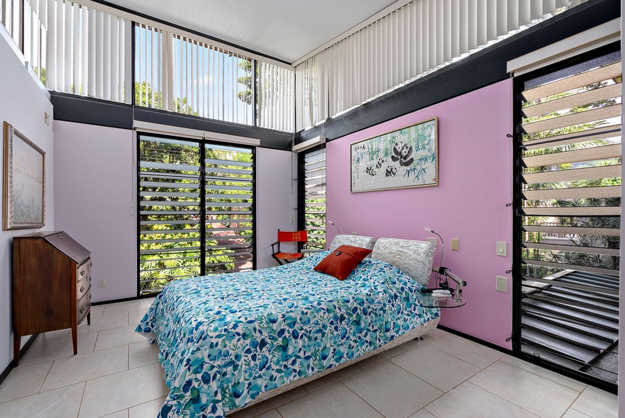 A vibrant guest suite with floor-to-ceiling windows and tropical garden views.