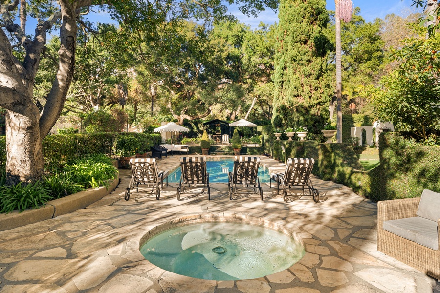 Your private oasis awaits with a sparkling pool and bubbling hot tub surrounded by lush gardens and elegant loungers.