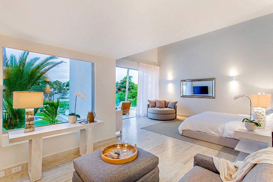 A bright and airy primary suite with comfortable seating and large windows offering serene views.