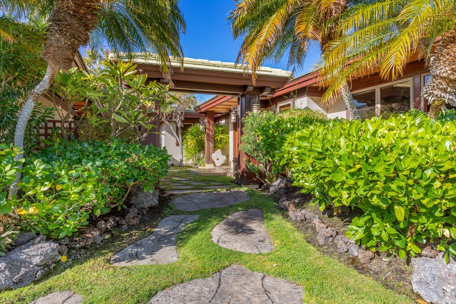 Stone path leads to the front door through lush landscaping.