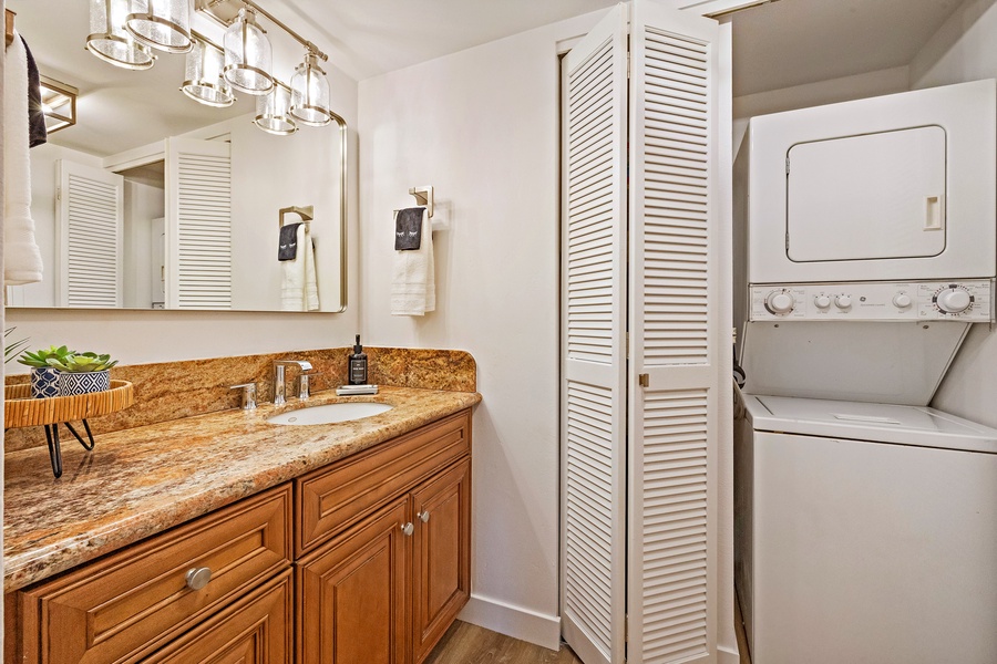 This bathroom offers practicality with a convenient in-unit washer and dryer tucked away behind the folding doors