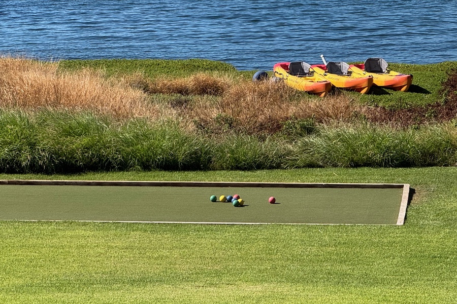 Seaside bocce lane with kayaks and calm blue water beyond.