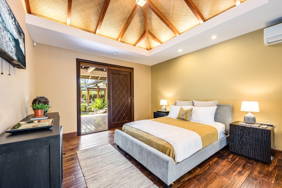 Warmly lit guest bedroom with high ceilings, split AC, and direct outdoor access.