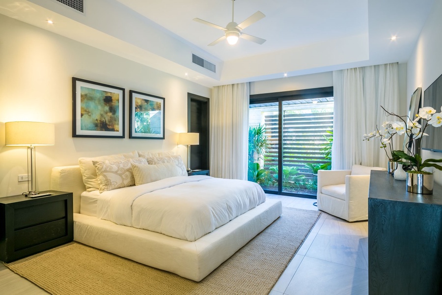 Inviting guest bedroom with a cozy bed and garden views through large windows.