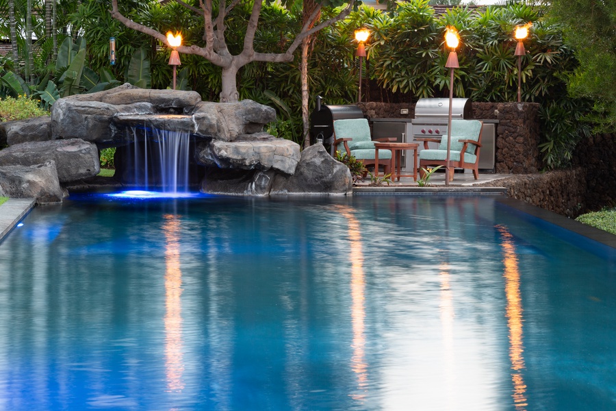 Resort-style pool with rock waterfall feature, perfect for tropical relaxation.