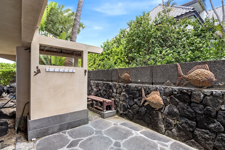 Private outdoor shower with stone flooring and lush greenery—rinse off post-beach in pure island style.