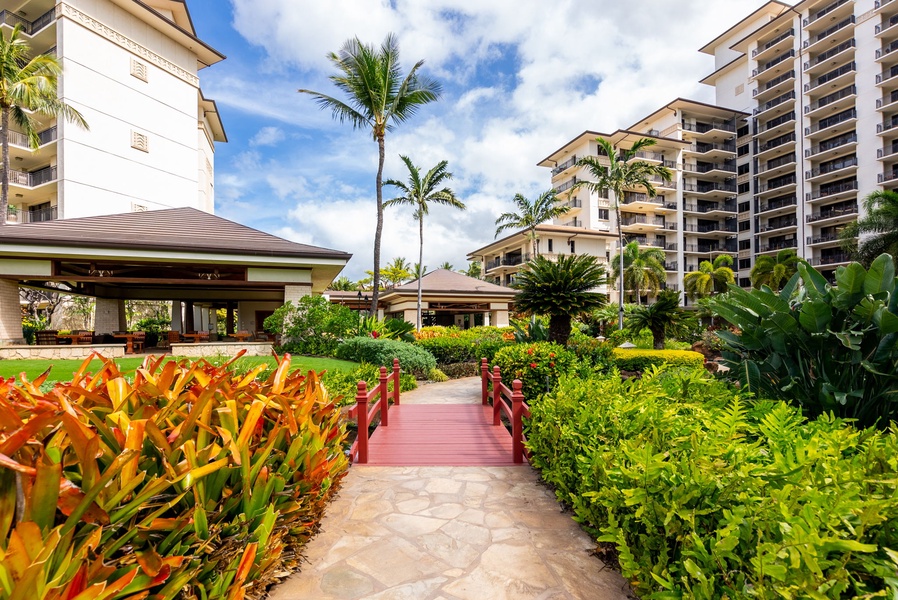 Tropical resort grounds with lush gardens, palm trees, and resort buildings create a paradise setting.