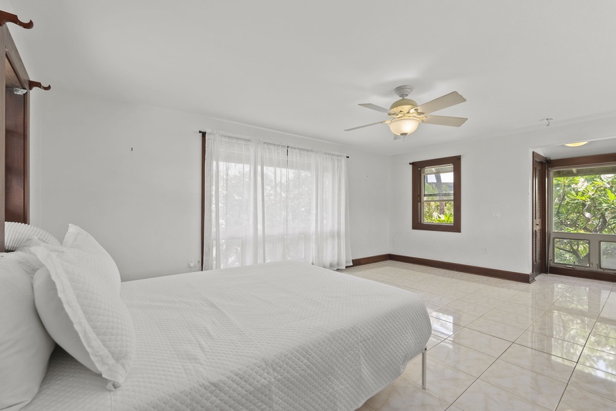 Bright guest bedroom with ceiling fan and private outdoor access.