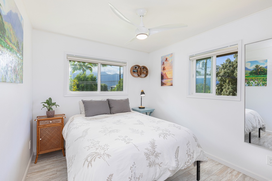 Second bedroom with queen bed, dual aspect windows, and breezy mountain views.